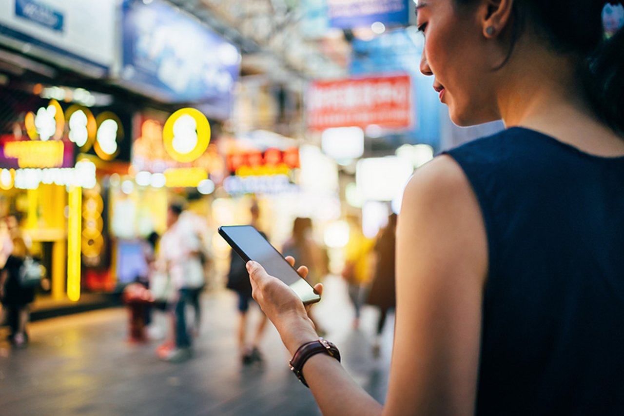 Woman Using Smartphone Woman using smartphone in busy city street, against colourful neon commercial sign and city buildings